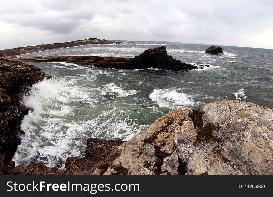 View of a furious wave hitting the cliffs on the coastline of Alentejo, Portugal. View of a furious wave hitting the cliffs on the coastline of Alentejo, Portugal.