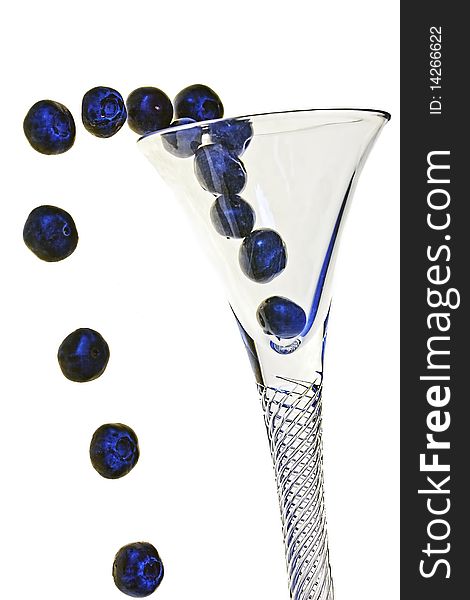Fresh blueberries appear to be popping out of a crystal cocktail glass on an isolated white background. Fresh blueberries appear to be popping out of a crystal cocktail glass on an isolated white background