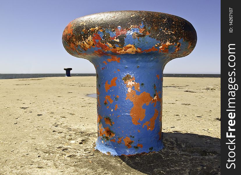 Blue and Red paint chipped heavy nautical bollard at the end of a Lake Michigan pier. Blue and Red paint chipped heavy nautical bollard at the end of a Lake Michigan pier