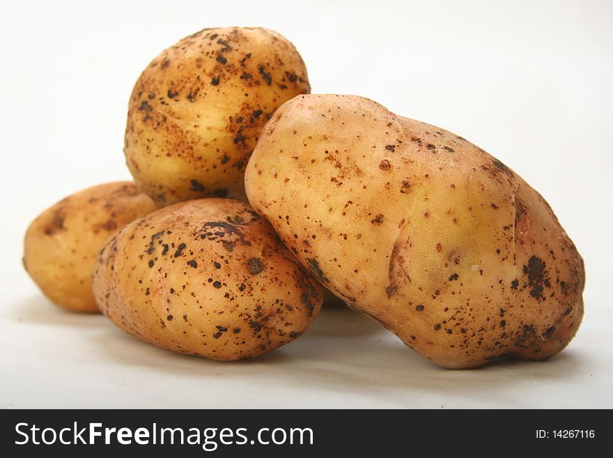 A heap of harvested crude potatoes on white