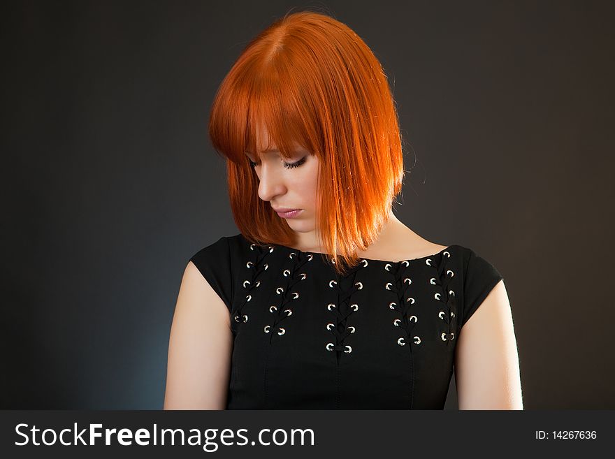 Beautiful red girl in an evening dress against a dark background. Beautiful red girl in an evening dress against a dark background