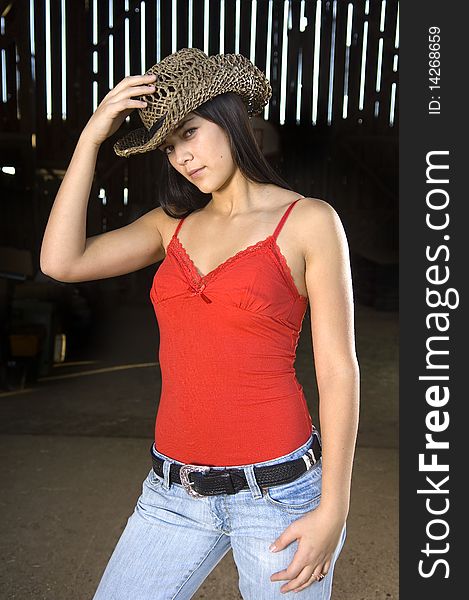 Cowgirl in barn doorway with hat and tank top