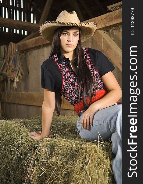 Cowgirl posing on hay with vest and hat. Cowgirl posing on hay with vest and hat