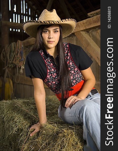 Cowgirl posing on hay with vest and hat. Cowgirl posing on hay with vest and hat