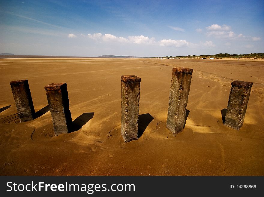 Old posts on a deserted beach. Taken with a wide angle lens and polariser filter. Old posts on a deserted beach. Taken with a wide angle lens and polariser filter.