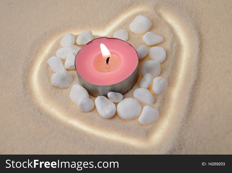 Valentine decoration still life scene - pink candle, white stones and a hearth symbol