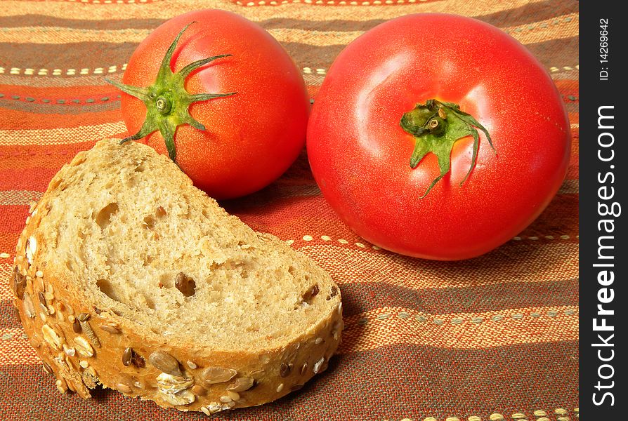 A piece of bread with tomatoes on a striped tablecloth