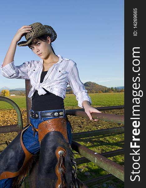 Cowgirl on fence with Fall background