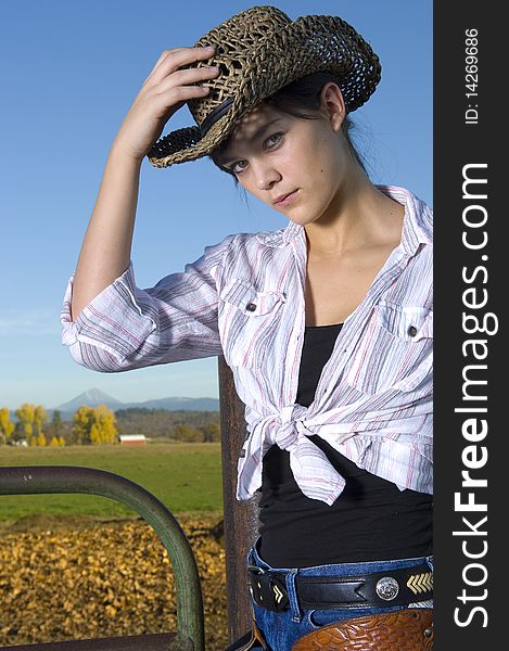 Cowgirl on fence with Fall background