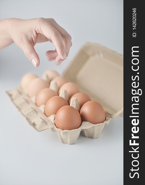 Hand are picking chicken eggs are arranged in a gradient color tone in eco carton on white background.perspective view. Hand are picking chicken eggs are arranged in a gradient color tone in eco carton on white background.perspective view