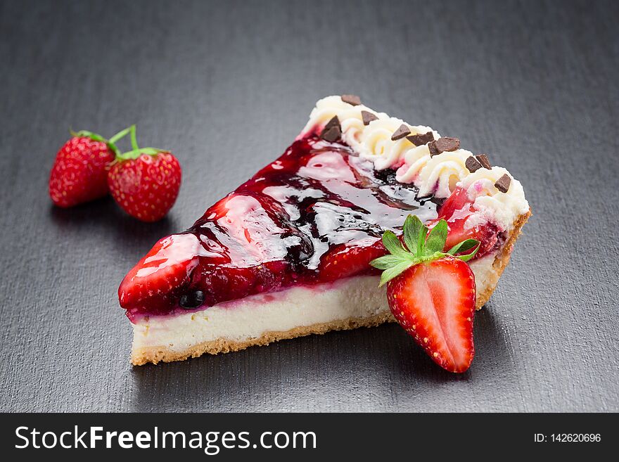 Strawberry cheesecake slice close up on a dark background