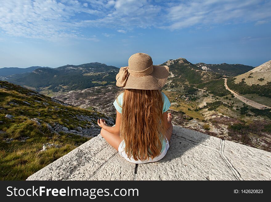 Girl on mountain top sitting and admire the view on a beautiful sunny summer day