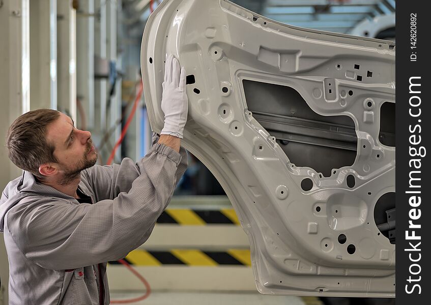 An employee of the car body painting shop checks the quality