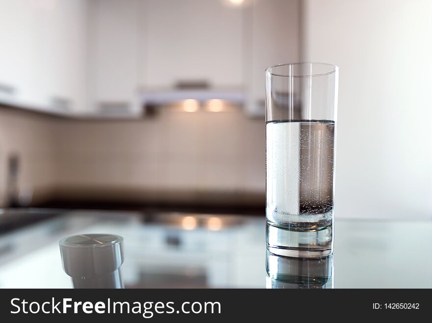 A glass of fresh water on the background of a modern kitchen. With copy space for your design.