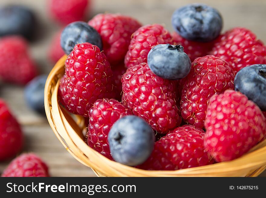 Raspberries and blueberries in a basket on a wooden table
shallow DOF