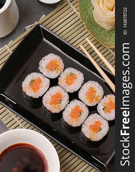 Japanese Restaurant, Sushi Roll On Black Slate Plate. Set For One Person With Chopsticks, Ginger, Soy, Top View, Copy