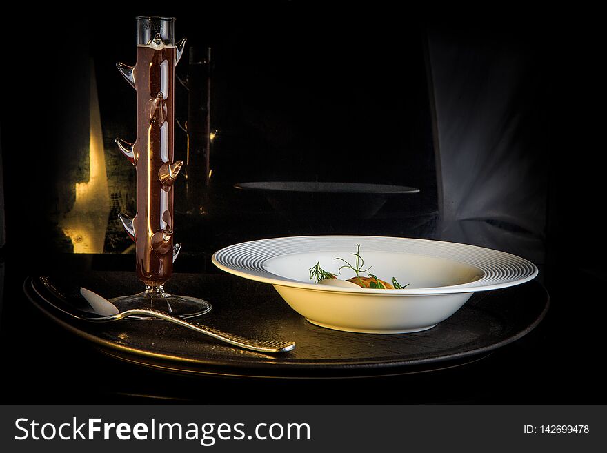 Vegetarian soup with mushrooms, mozzarella cheese, and dill served in restaurant white plate and spoon on black background