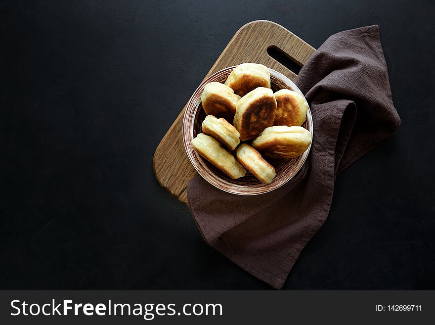 Fried patties or pies filled green onion and eggs on dark wooden background. Pirozhki Russian tradition food