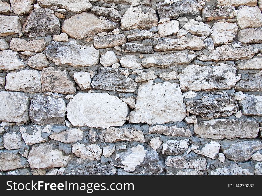 Aged wall is made of stones of different size. Aged wall is made of stones of different size