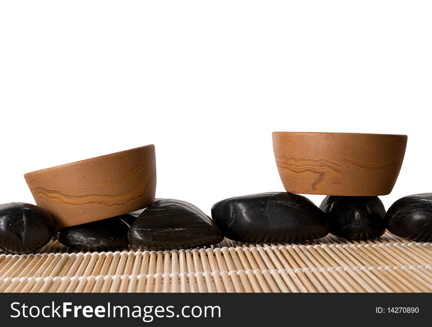 Two clay cups, mat and stones isolated in white