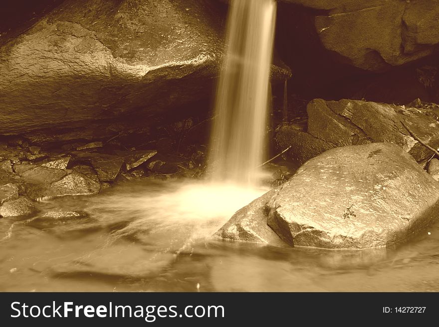 A small waterfall landing on rocks. A small waterfall landing on rocks