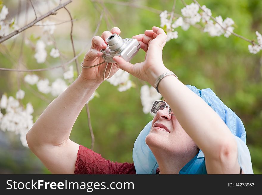 Beautiful senior woman taking photos outdoors in spring garden