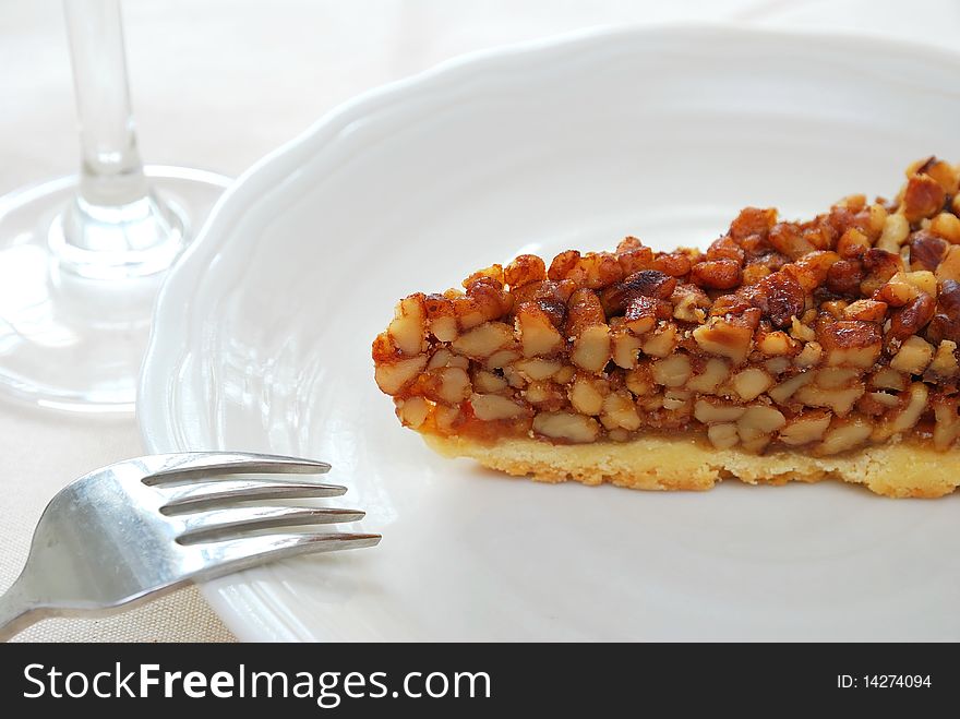 A single slice of hazel nut tart on white plate with fork. For concepts such as food and beverage, diet and nutrition, and healthy eating. A single slice of hazel nut tart on white plate with fork. For concepts such as food and beverage, diet and nutrition, and healthy eating.