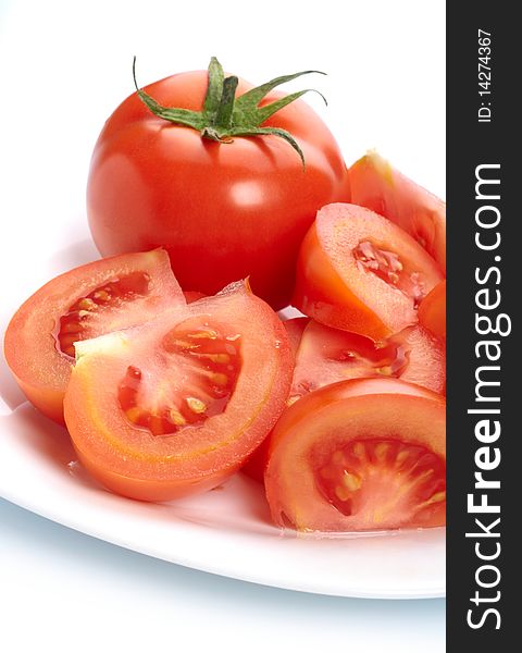 Tomato and slices on plate isolated on white background