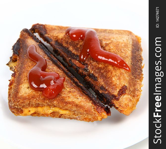 Toasted sandwich with cheese decorated with ketchup on a plate
