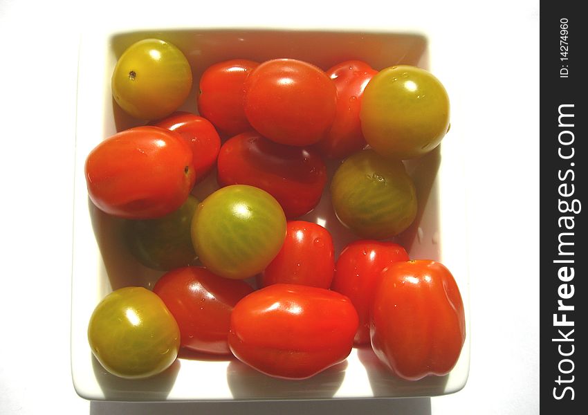 Some red and green tomatoes over white