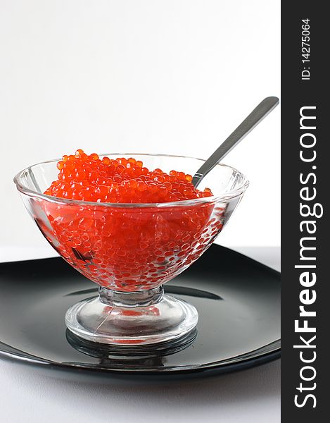 Red caviar in a glass vase on a black plate