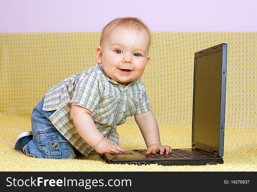 Kid plays with laptop on yelow background
