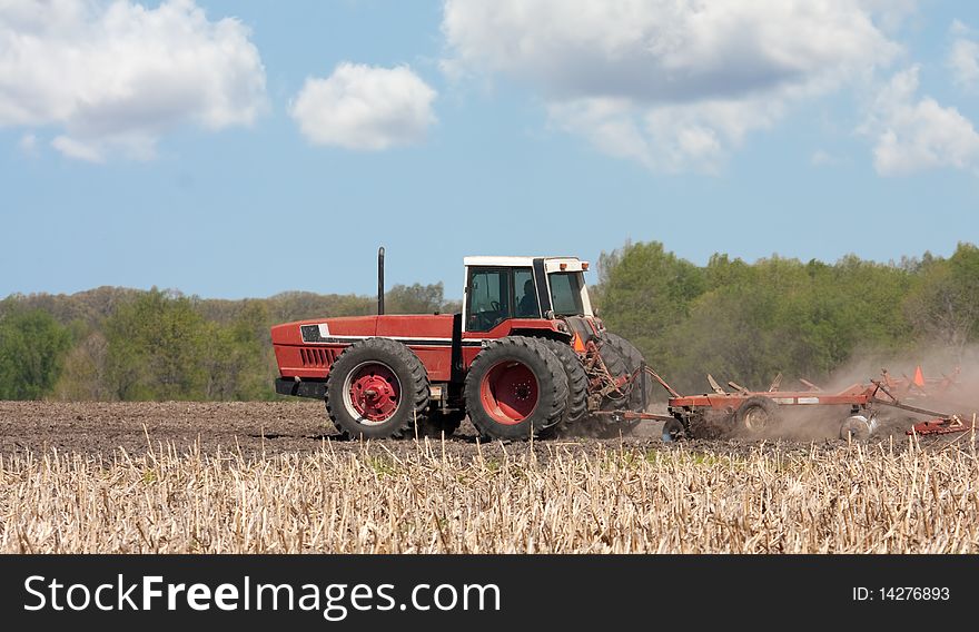 Farm tractor working in a field tilling the soil