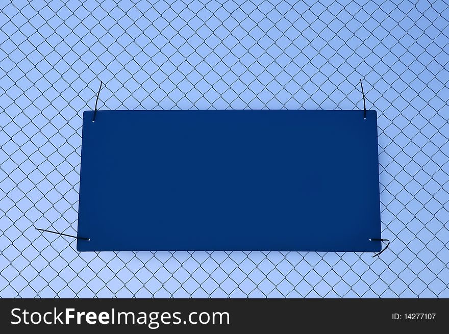 Blue sign tied to a fence left blank for copy. Blue sign tied to a fence left blank for copy