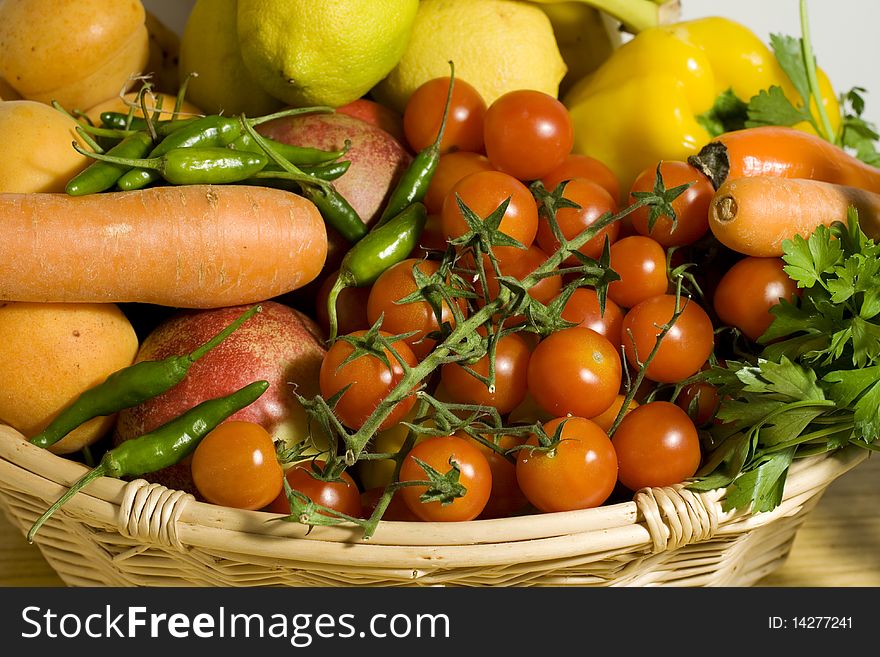 Carrot tomatoes and little green peppers inside a wicker basket. Carrot tomatoes and little green peppers inside a wicker basket