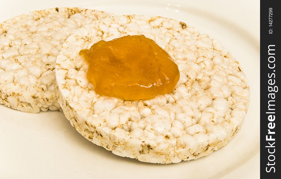 Rice biscuits with apricot jam on a white plate background