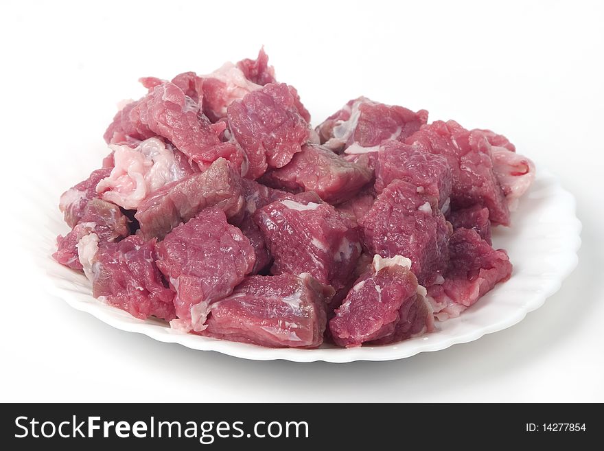 Small pieces of raw meat on white plate, chopped on little blocks. isolated on white background. Small pieces of raw meat on white plate, chopped on little blocks. isolated on white background.