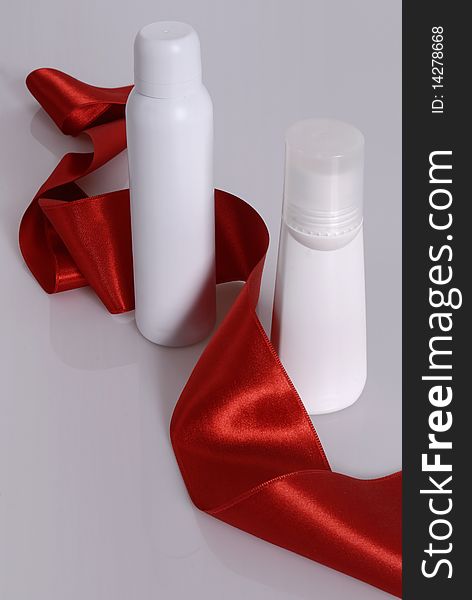 Blank deodorant packaging, spray and roll on, on a white background, arranged with a silk red ribbon. Blank deodorant packaging, spray and roll on, on a white background, arranged with a silk red ribbon.