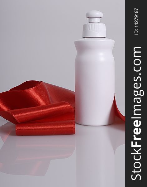Blank cosmetic packaging, white on white background, arranged with red ribbon. Hair product mock up. Blank cosmetic packaging, white on white background, arranged with red ribbon. Hair product mock up.
