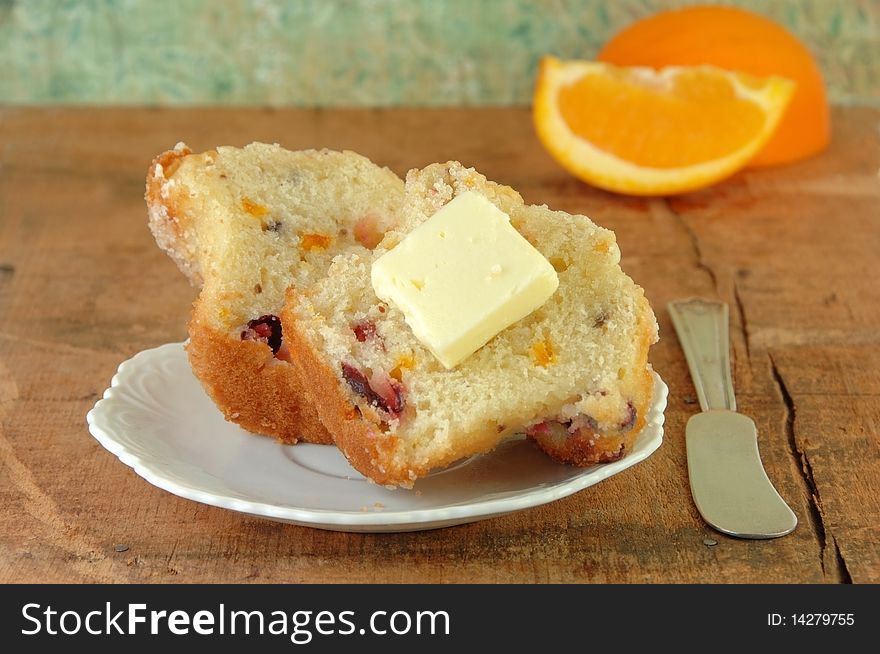 Muffin cut in half with butter. Oranges in the background. Muffin cut in half with butter. Oranges in the background.