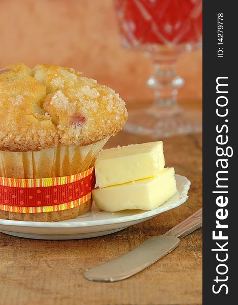 Fresh baked cranberry muffin with butter. Juice in the background. Fresh baked cranberry muffin with butter. Juice in the background.