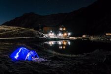 Night Mountain Landscape With Illuminated Blue Tent. Mountain Peaks And The Moon. Outdoor At Lacul Balea Lake, Transfagarasan, Stock Photography