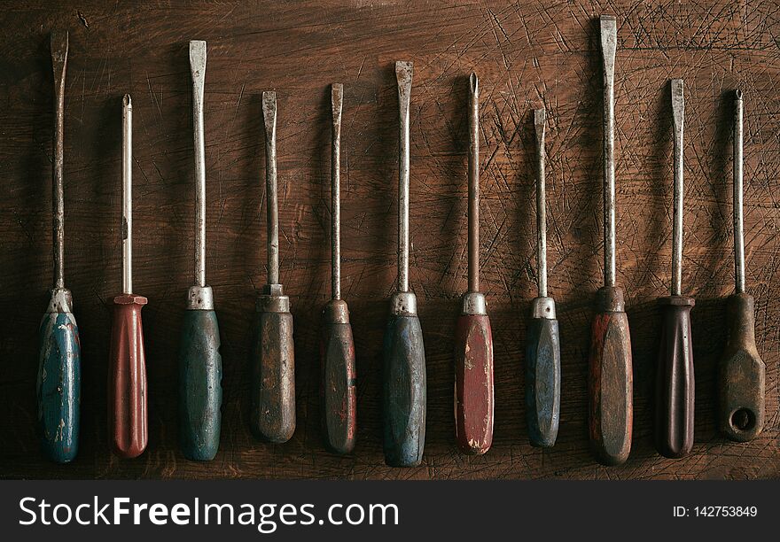 Neat row of old worn vintage screwdrivers with wooden handles on a rustic wood background panorama banner