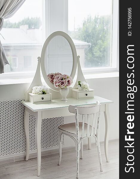 A beautiful white mirror on the table. Elegant bright interior. Close-up.