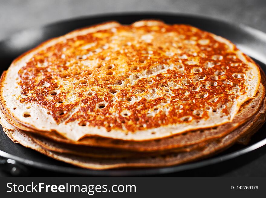 Stack of kefir pancakes in iron pan on Dark grey