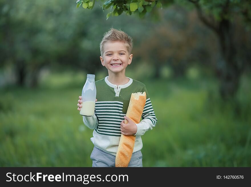 Cute child drinking milk outdoors. Cheerful boy on the picnic