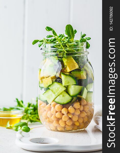 Green salad with chickpeas in a jar, white background, copy space. Detox, vegan food, plant based diet concept