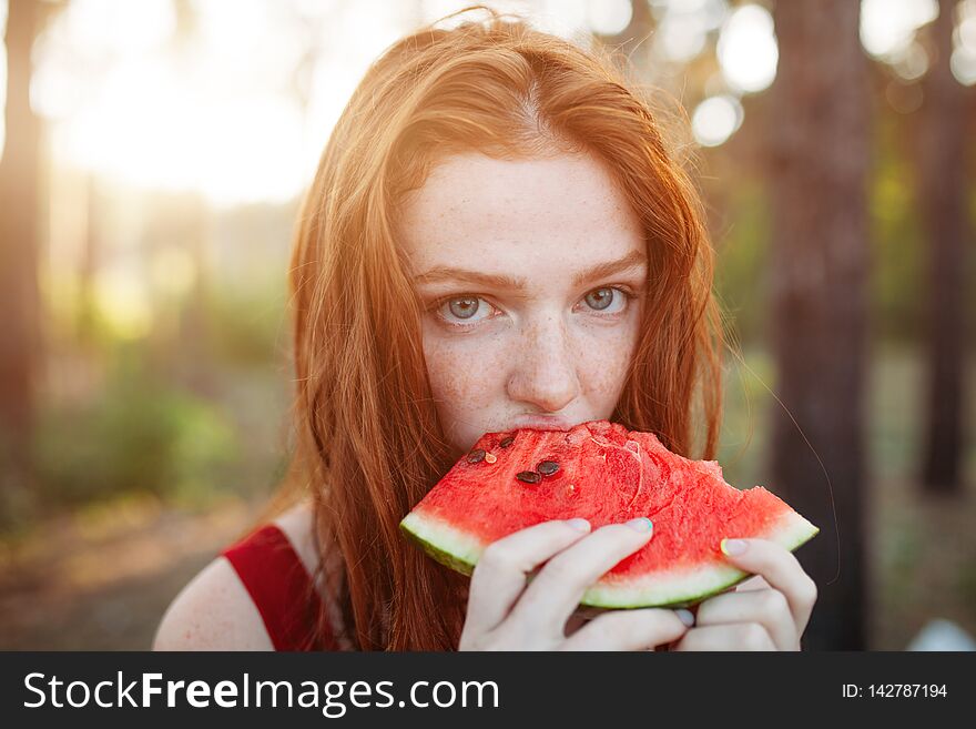 Happy young woman eating watermelon on the nature. Youth lifestyle. Happiness, joy, holiday, beach, summer concept