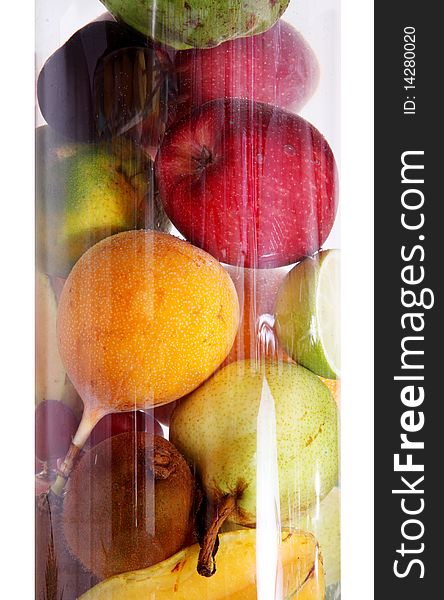 Fruits of different colors in a glass cylinder