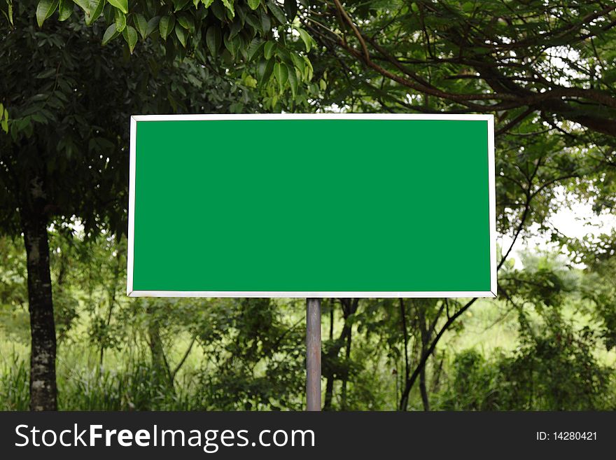A green sign with trees in the background. A green sign with trees in the background